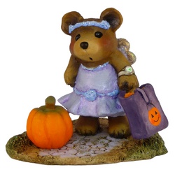 Bear in a party frock with wings and a candy bag, standing by a pumpkin