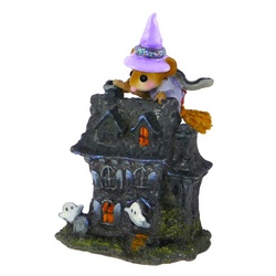 A Whitch pearers over the roof of miniture haunted house
