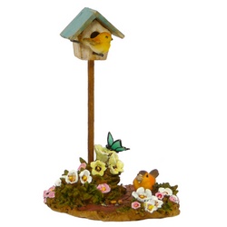 Birdhouse on a stick with two birds and flowers around base