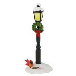 Street lamp in the snow with wreath under lamp and bird at base