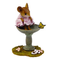 Young girl mouse sits on the edge of a bird bath bathing her feet whatching a butterfly