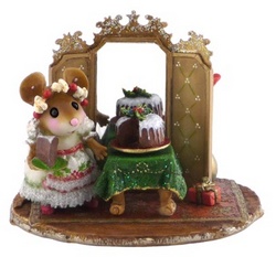 Hostess stands by large Christmas cake on a table in front of mirror screen