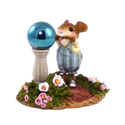 Child mouse pulls a face in front of a garden gazing ball