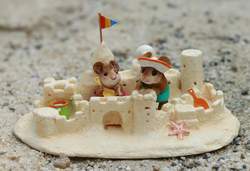 two tiny beach mice hard at work building the ultimate sandcastle,